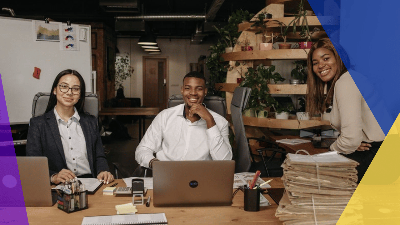 hiring in Colombia - three professionals smiling at their desks in a modern office